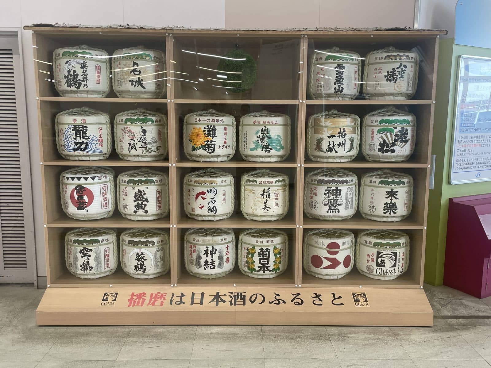 飾り樽が並ぶ棚。台座に「播磨は日本酒のふるさと」と書かれている