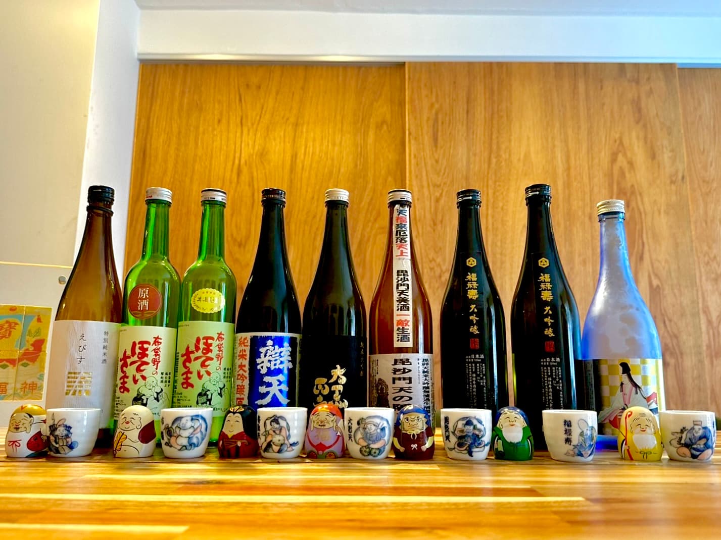 七福神の名を持つ日本酒の瓶と、七福神が描かれた盃を並べた記録写真